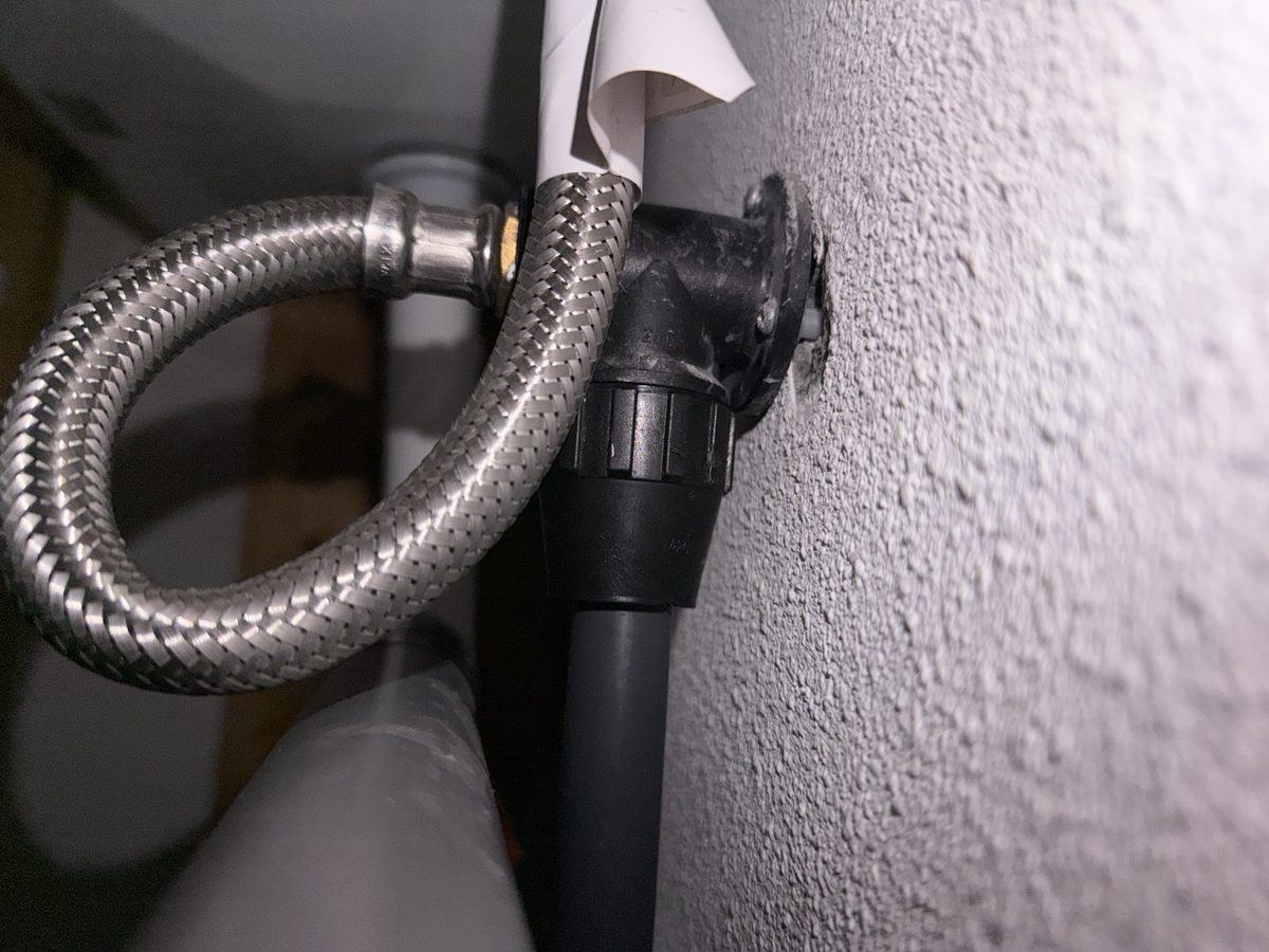 Wasmachineaansluiting met flexibele slang en afvoer tegen een wand